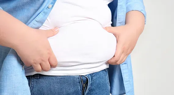 Person holding excess abdominal fat during a weight management journey